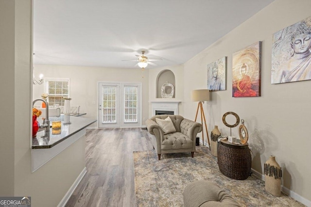 sitting room with hardwood / wood-style floors and ceiling fan with notable chandelier