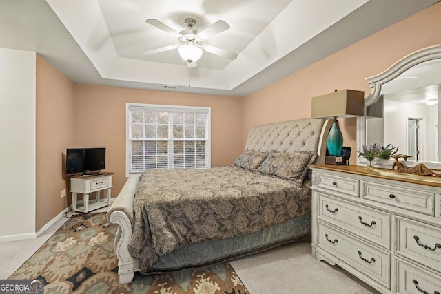 carpeted bedroom with a tray ceiling and ceiling fan