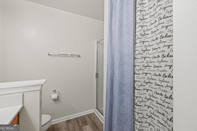 bathroom featuring hardwood / wood-style flooring, an enclosed shower, and toilet