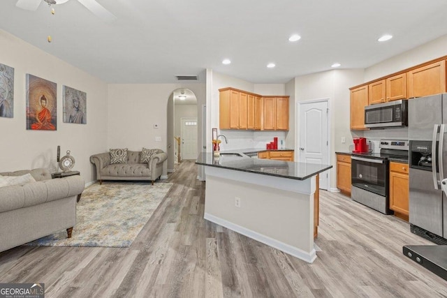 kitchen with appliances with stainless steel finishes, kitchen peninsula, sink, and light wood-type flooring