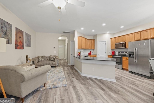 kitchen with sink, kitchen peninsula, ceiling fan, stainless steel appliances, and light hardwood / wood-style floors