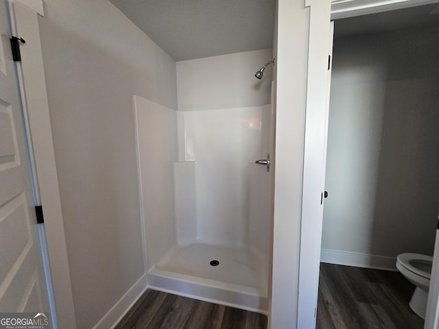 bathroom with wood-type flooring, a shower, and toilet