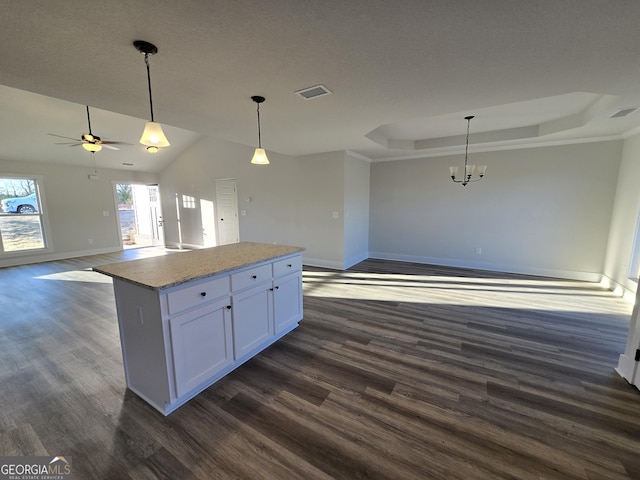 kitchen featuring white cabinetry, a tray ceiling, light stone countertops, and hanging light fixtures