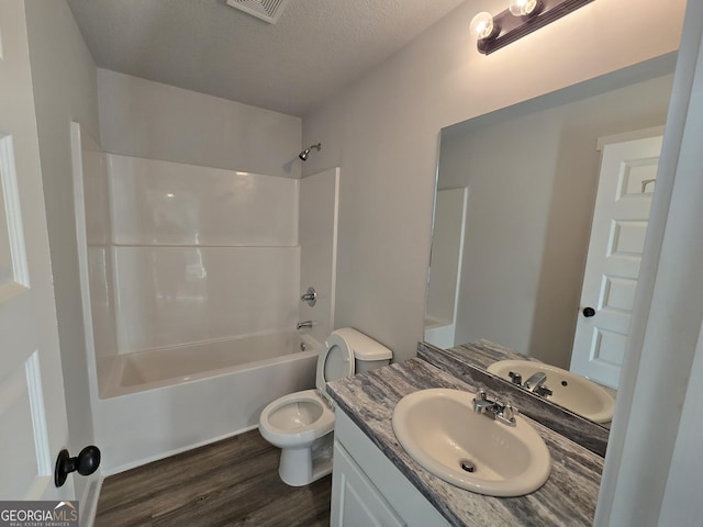 full bathroom featuring shower / bathing tub combination, vanity, wood-type flooring, a textured ceiling, and toilet