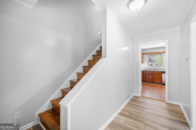 staircase featuring crown molding, sink, and hardwood / wood-style floors