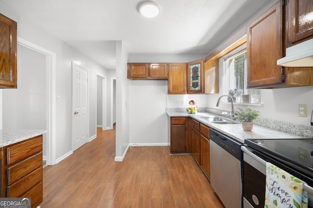 kitchen featuring stainless steel appliances, light stone countertops, sink, and light hardwood / wood-style floors