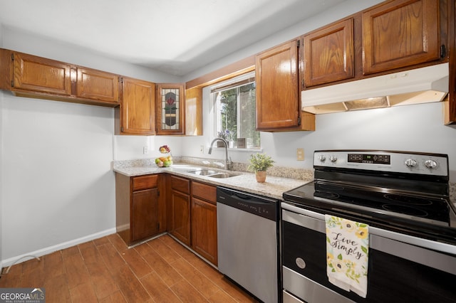 kitchen with light stone counters, sink, stainless steel appliances, and light hardwood / wood-style floors