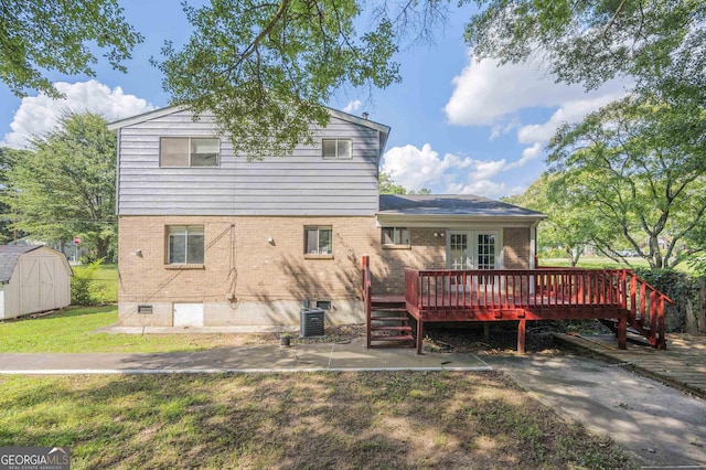 back of house with a wooden deck, central AC unit, a shed, and a lawn