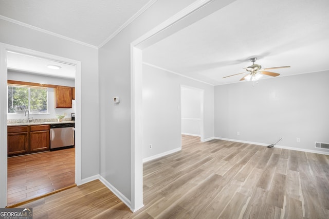 empty room featuring sink, crown molding, ceiling fan, and light wood-type flooring