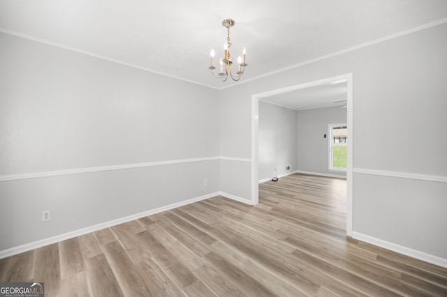 spare room with hardwood / wood-style flooring, crown molding, and a notable chandelier