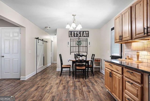 dining space with a barn door, dark hardwood / wood-style floors, and a notable chandelier