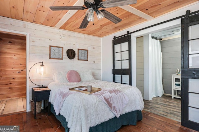 bedroom featuring dark wood-type flooring, wooden ceiling, a barn door, and wooden walls