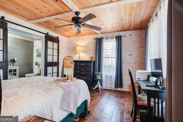 bedroom with a barn door, dark hardwood / wood-style floors, wooden ceiling, and wooden walls