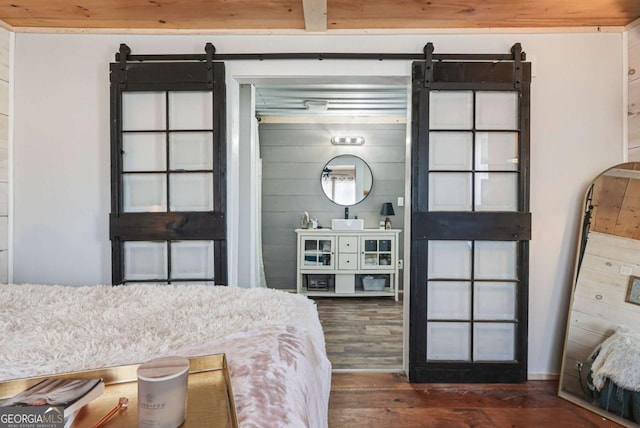 bedroom with dark wood-type flooring and a barn door