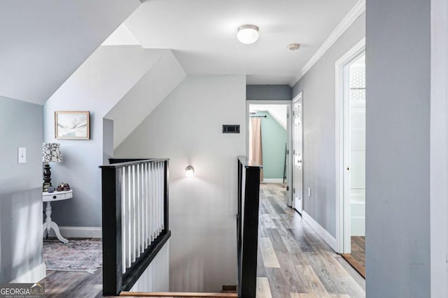 corridor featuring lofted ceiling, ornamental molding, and light hardwood / wood-style floors