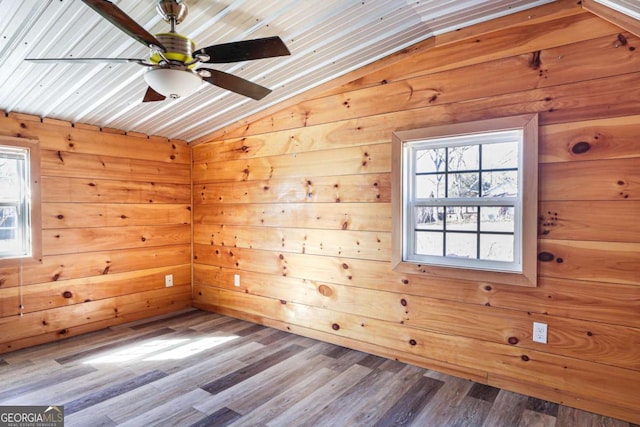 spare room featuring hardwood / wood-style flooring, vaulted ceiling, and wooden walls