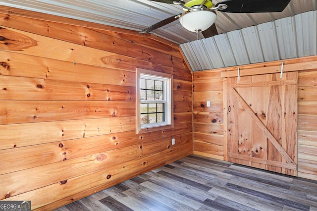 empty room with vaulted ceiling, dark wood-type flooring, and wooden walls