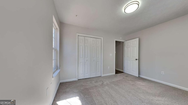 unfurnished bedroom featuring light carpet, a textured ceiling, and a closet