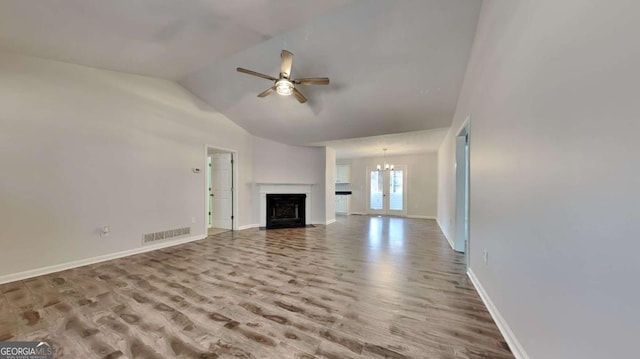 unfurnished living room with hardwood / wood-style flooring, vaulted ceiling, and ceiling fan with notable chandelier