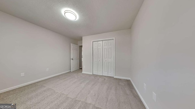 unfurnished bedroom featuring light colored carpet, a closet, and a textured ceiling