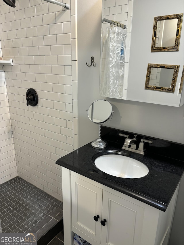 bathroom featuring tiled shower and vanity