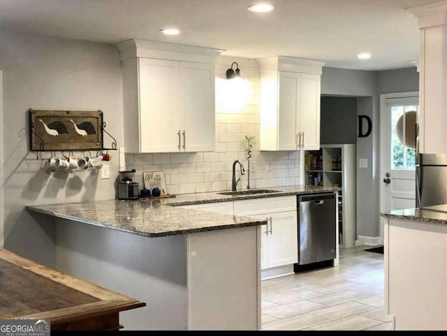 kitchen featuring dishwasher, dark stone countertops, and white cabinets