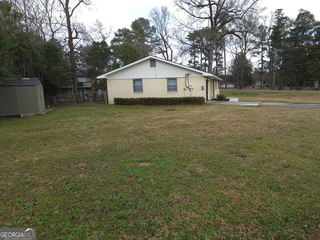 ranch-style home featuring a storage shed and a front lawn