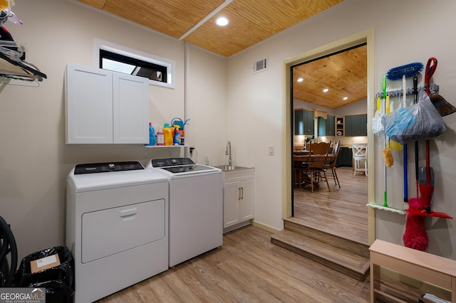 clothes washing area with sink, wood ceiling, cabinets, and washing machine and clothes dryer