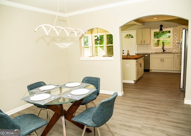 dining space featuring light wood-style flooring, a wealth of natural light, and ornamental molding