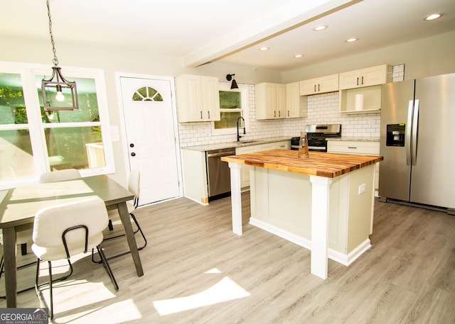 kitchen featuring a wealth of natural light, wooden counters, stainless steel appliances, and a sink