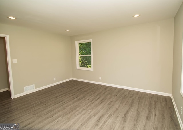 unfurnished room featuring recessed lighting, wood finished floors, visible vents, and baseboards