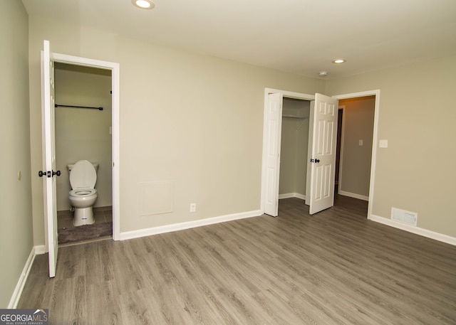 unfurnished bedroom with visible vents, baseboards, and wood finished floors