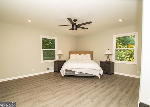 bedroom with visible vents, multiple windows, baseboards, and wood finished floors