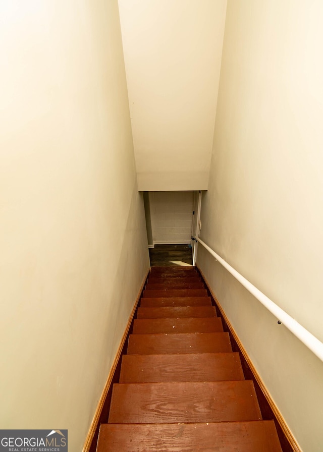 stairs featuring lofted ceiling and wood finished floors