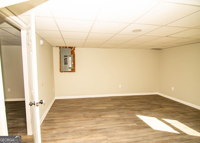 finished basement with electric panel, baseboards, a paneled ceiling, and wood finished floors