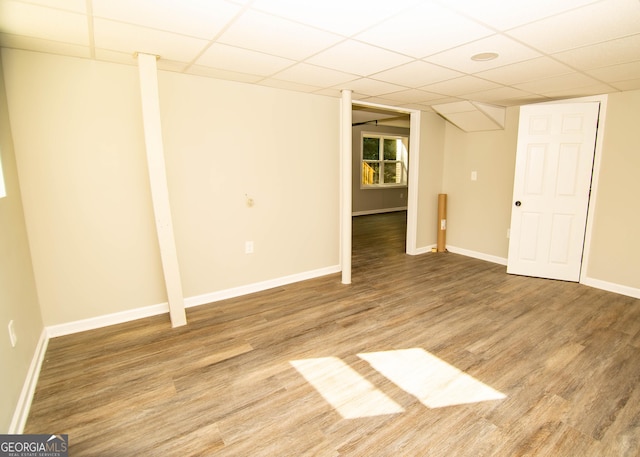 basement featuring a drop ceiling, baseboards, and wood finished floors