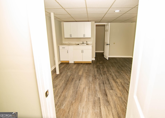 kitchen featuring baseboards, dark wood finished floors, light countertops, a paneled ceiling, and white cabinetry