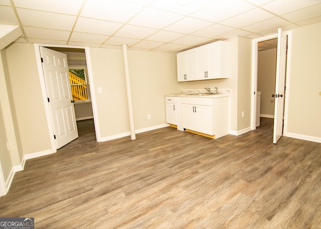 interior space featuring light wood-style flooring, a paneled ceiling, baseboards, and a sink