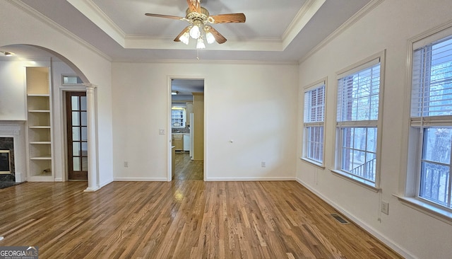 interior space featuring crown molding, a tray ceiling, a high end fireplace, and hardwood / wood-style flooring