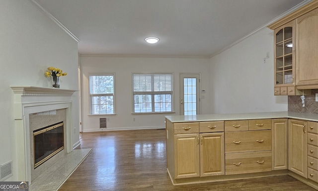 kitchen with crown molding, light brown cabinets, dark hardwood / wood-style flooring, kitchen peninsula, and a premium fireplace