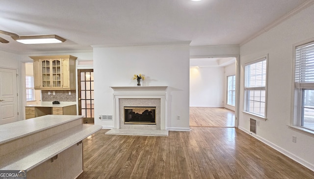 unfurnished living room featuring hardwood / wood-style floors, a high end fireplace, and ornamental molding