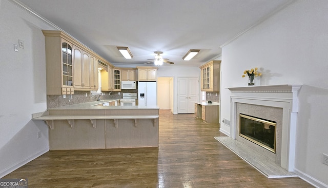 kitchen with tasteful backsplash, a kitchen breakfast bar, dark hardwood / wood-style flooring, kitchen peninsula, and white appliances