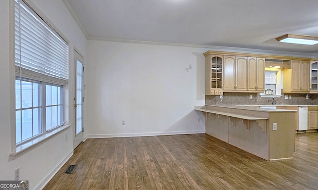 kitchen featuring light brown cabinetry, decorative backsplash, a breakfast bar area, and kitchen peninsula