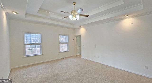 empty room with light carpet, a tray ceiling, ornamental molding, and ceiling fan