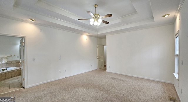 carpeted spare room with crown molding, a tray ceiling, and ceiling fan