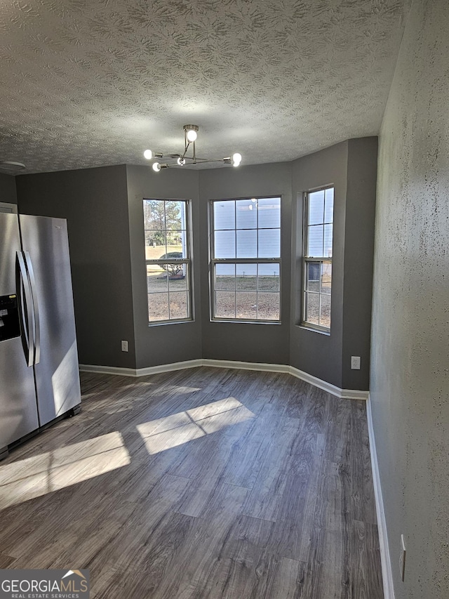 unfurnished dining area with plenty of natural light, dark hardwood / wood-style floors, and a textured ceiling