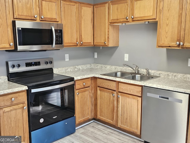 kitchen featuring appliances with stainless steel finishes, light hardwood / wood-style floors, and sink