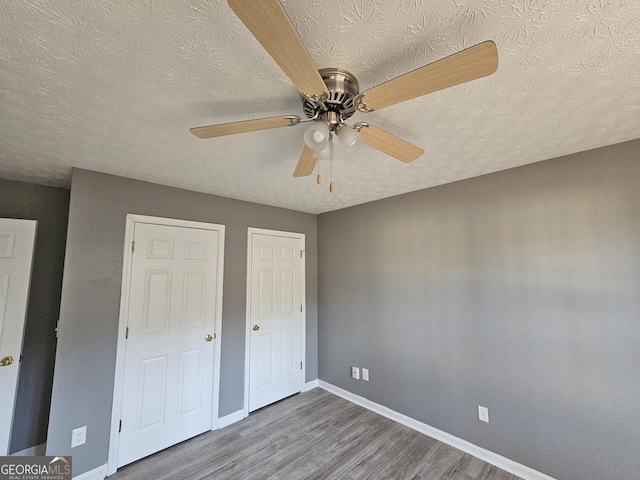 unfurnished bedroom featuring ceiling fan, hardwood / wood-style floors, and a textured ceiling