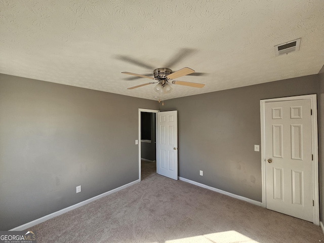 unfurnished bedroom with ceiling fan, light carpet, and a textured ceiling