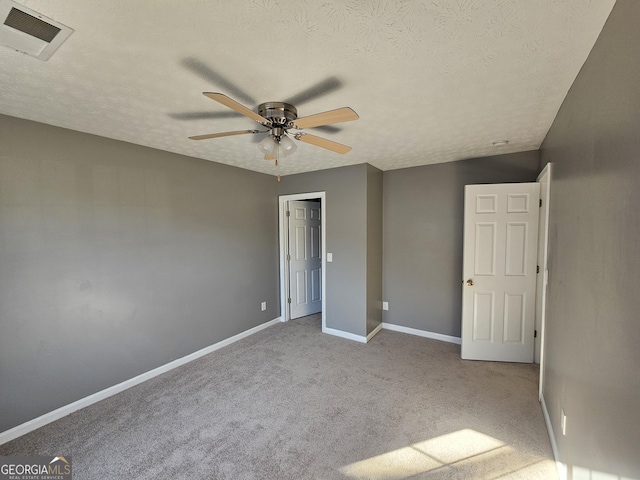 unfurnished bedroom with light carpet, ceiling fan, and a textured ceiling